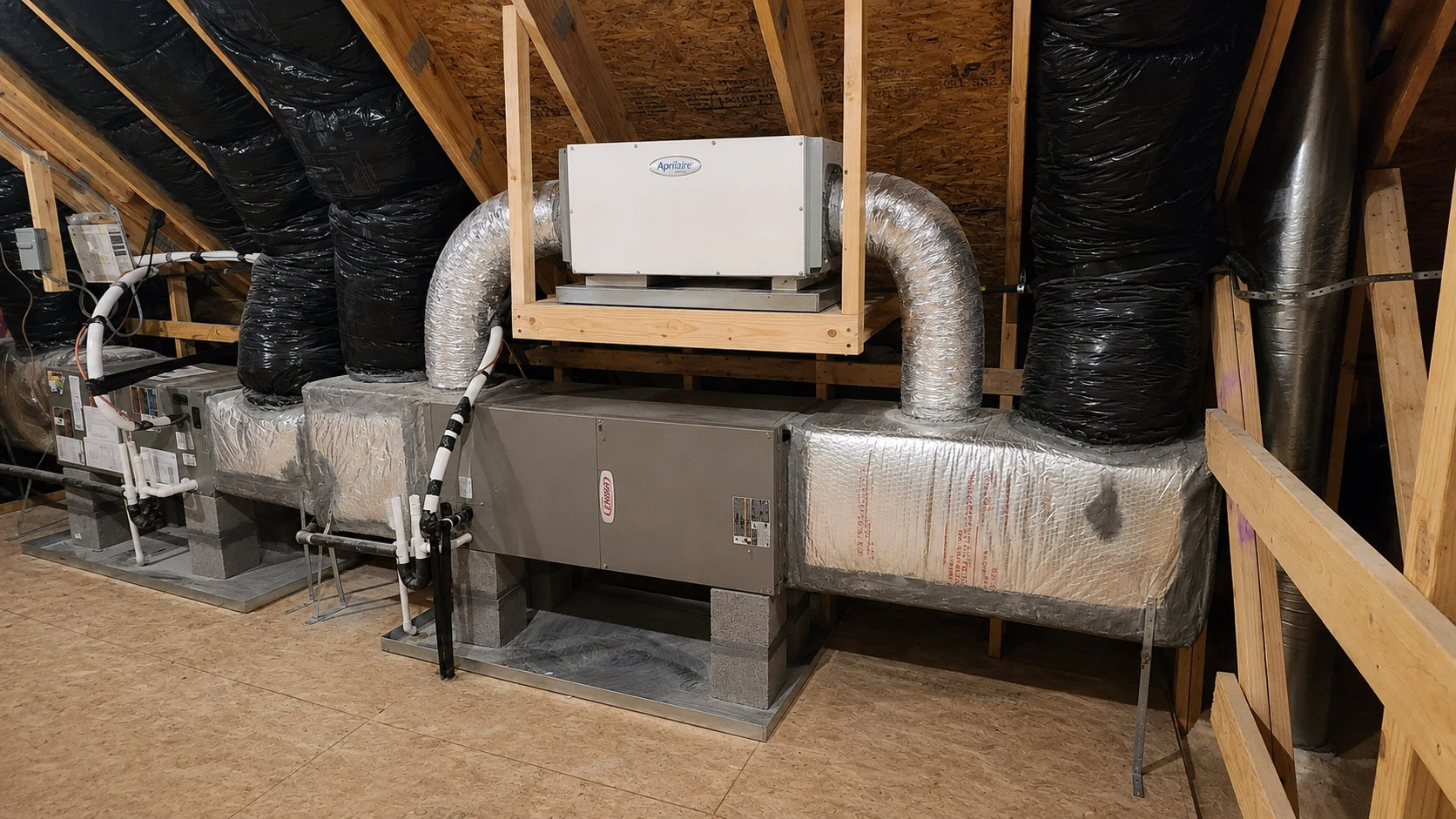 AprilAire whole-house dehumidifier installed on a platform above dual Lennox air handlers in an attic mechanical room in Raleigh NC — Triangle Dehumidifiers installation