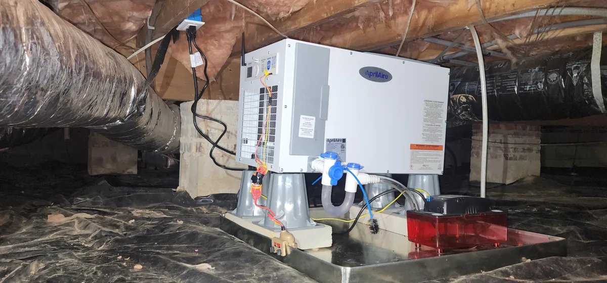 AprilAire crawl space dehumidifier mounted on blocks with condensate line and filter access in a Wake County NC crawl space
