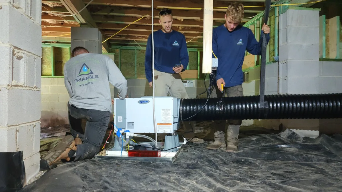 Triangle Dehumidifiers crew connecting a condensate drain line to a newly installed AprilAire dehumidifier in a Wake County NC crawl space