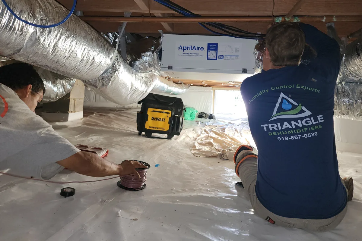 Triangle Dehumidifiers technicians installing an AprilAire ERV in an encapsulated crawl space in Raleigh NC